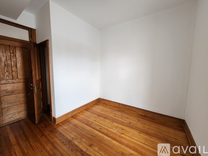 A room with wooden floors and a white wall with a door.