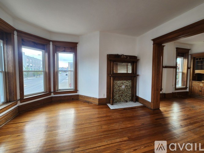 A room with wooden floors and a fireplace with a stone surround.