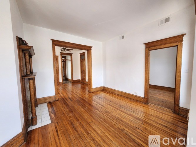 A room with wooden floors and white walls, with a mirror on the right wall.