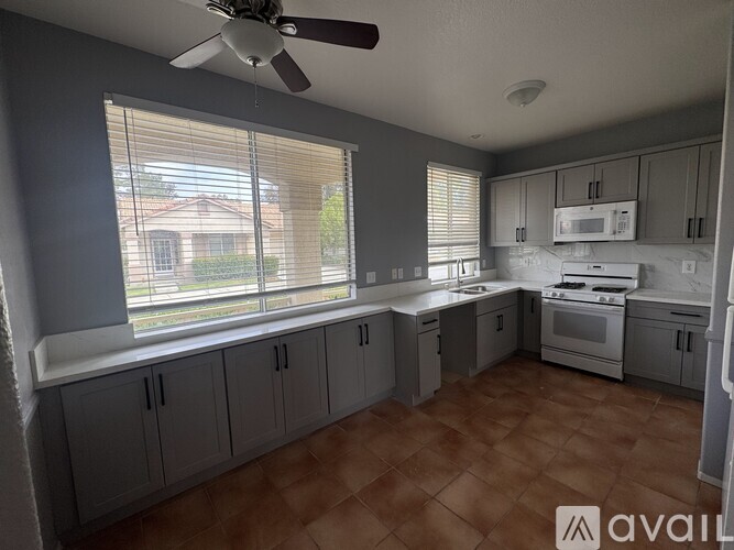 A kitchen with a fan on the ceiling and a window with blinds.