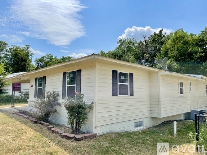 A beige house with a red door and a small garden in front.