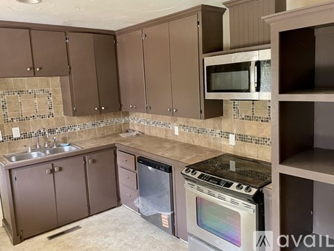 A kitchen with brown cabinets and a tiled backsplash.