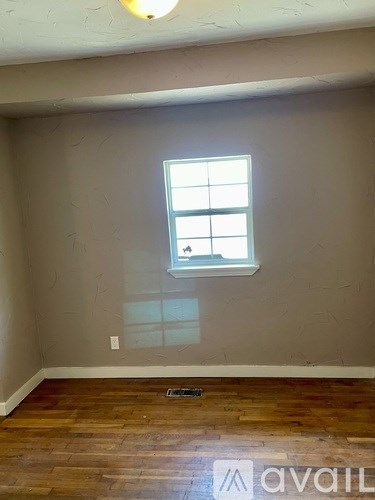 A room with a window and wooden floors.