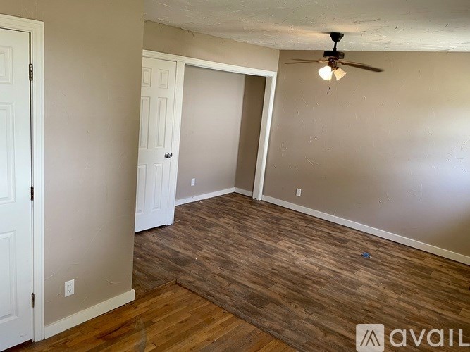 A room with a ceiling fan and wooden flooring.