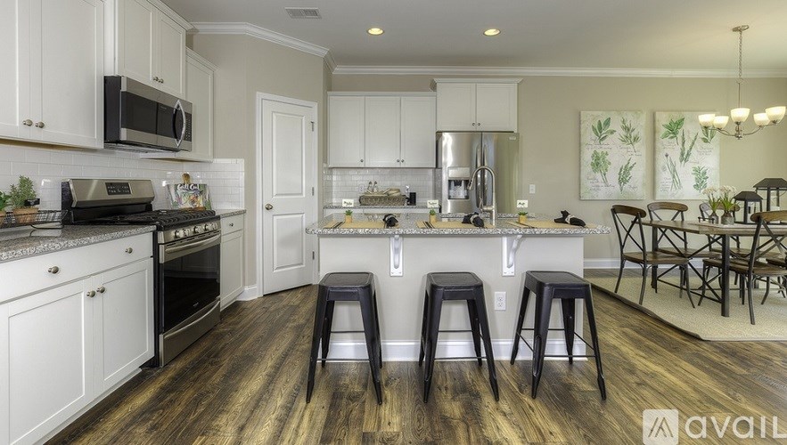A kitchen with white cabinets and a dark wood floor.