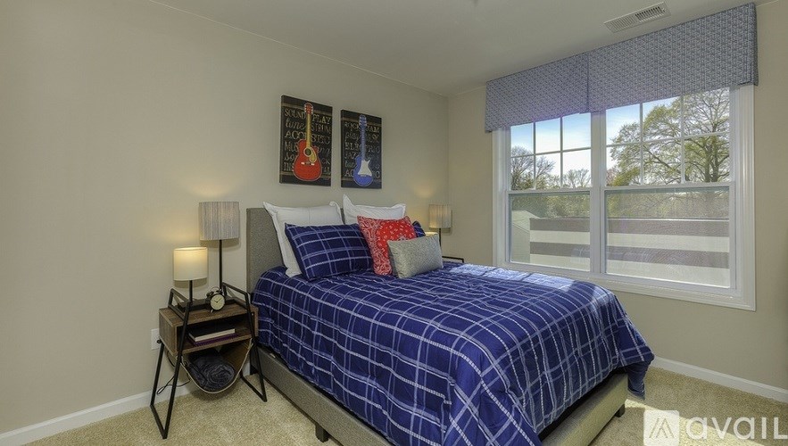 A bedroom with a bed, nightstand, and two guitar posters on the wall.