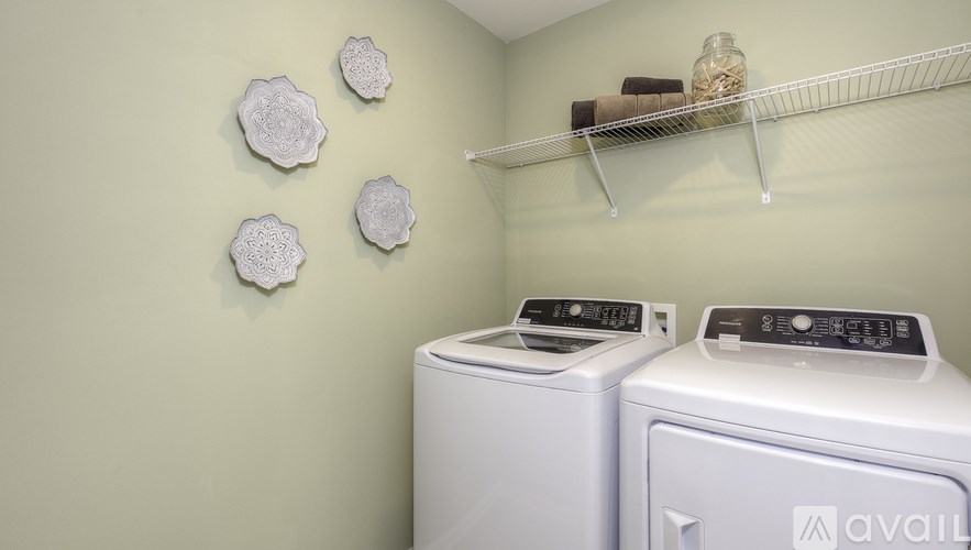 A laundry room with two washing machines and a shelf with jars on it.