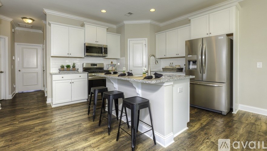 A kitchen with white cabinets and a wooden floor.