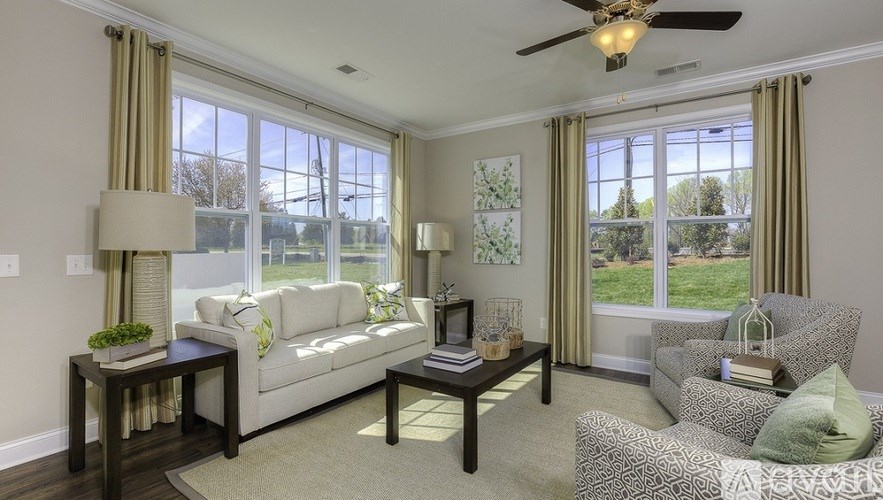A sunny living room with a white sofa and a grey armchair.