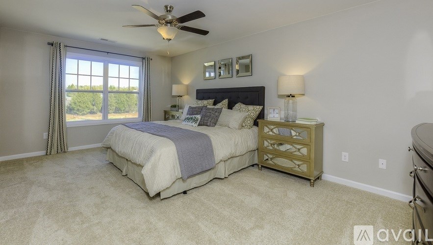A bedroom with a bed, dresser, and ceiling fan.
