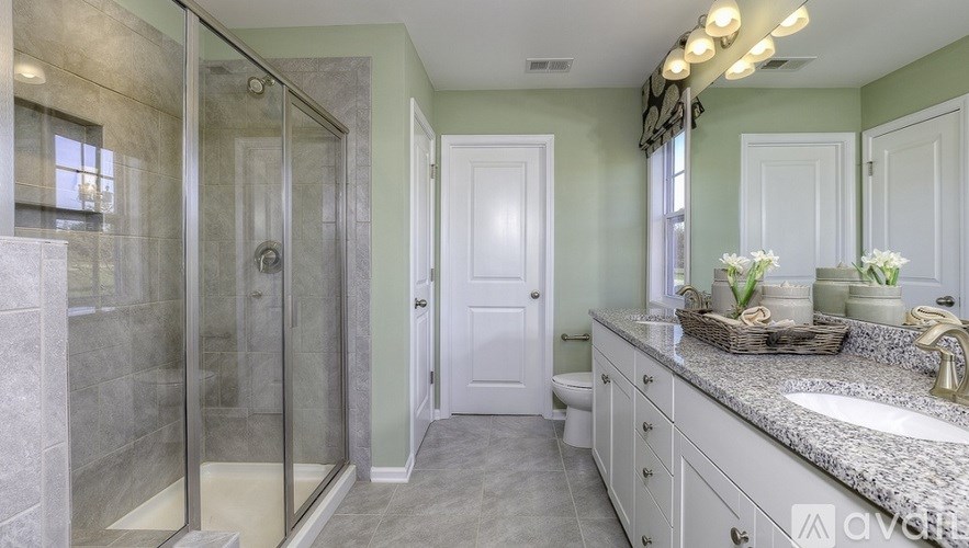 A bathroom with a walk-in shower, white door, and a vanity with a marble countertop.