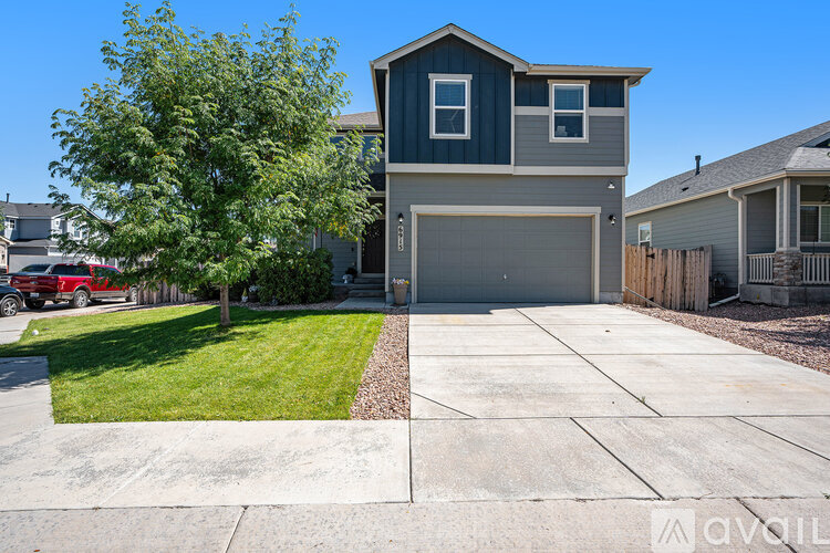 A two-story house with a garage and a tree in front.