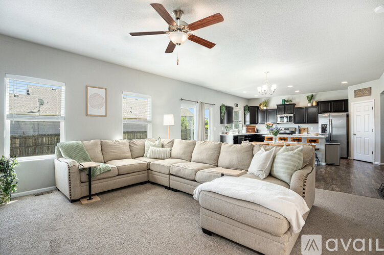 A living room with a beige sofa and a ceiling fan.