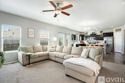 A living room with a beige sofa and a ceiling fan.