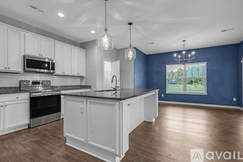 A kitchen with white cabinets and a black countertop.