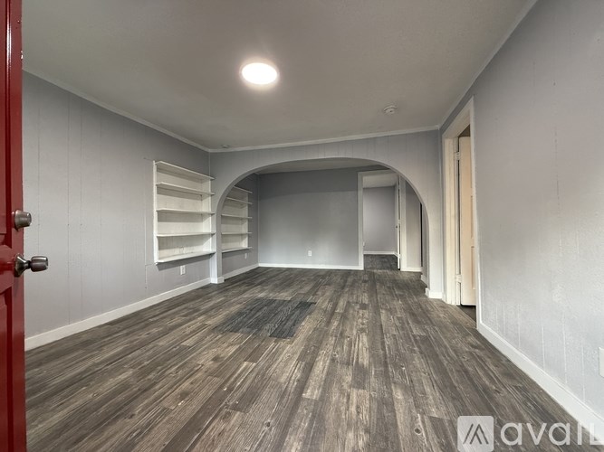 A room with wooden flooring and a red door.