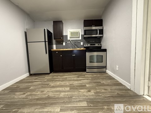 A kitchen with a refrigerator, oven, and microwave.