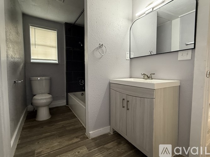 A bathroom with a toilet, sink, and mirror.