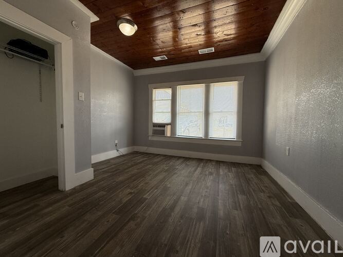 A room with wooden floors and a window with blinds.
