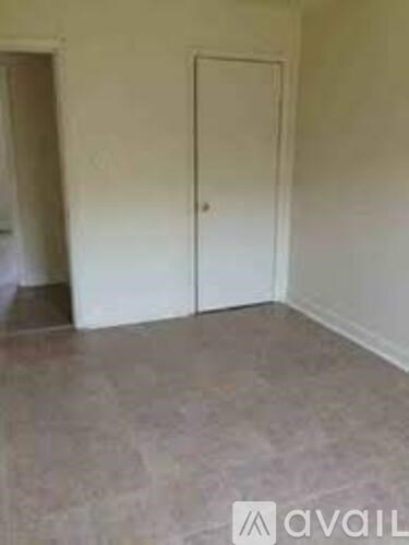 A room with a white door and a carpeted floor.