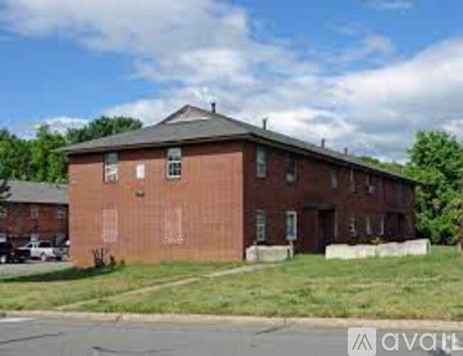 A red brick building with a grassy area in front.