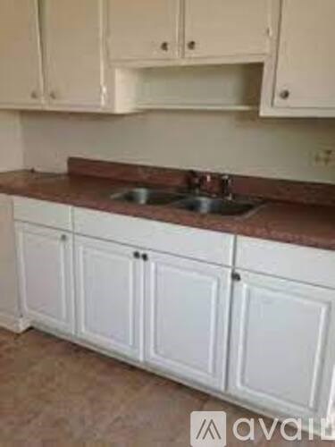 A kitchen with white cabinets and a brown countertop.