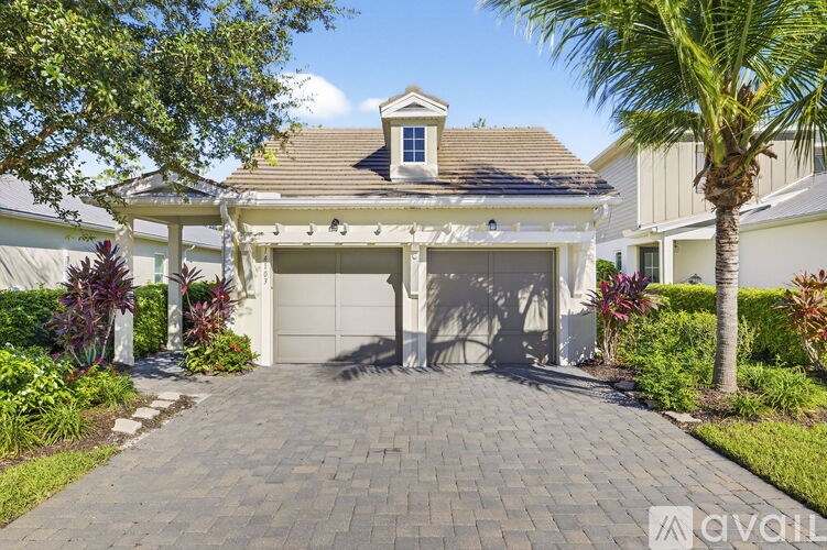 A house with a driveway and a palm tree in front.