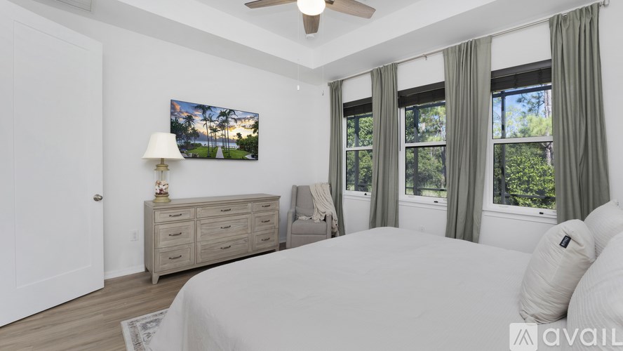 A bedroom with a large bed, a dresser, and a television mounted on the wall.