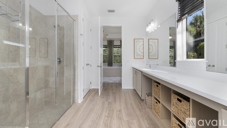 A bathroom with a walk-in shower, a vanity with a mirror, and a window.