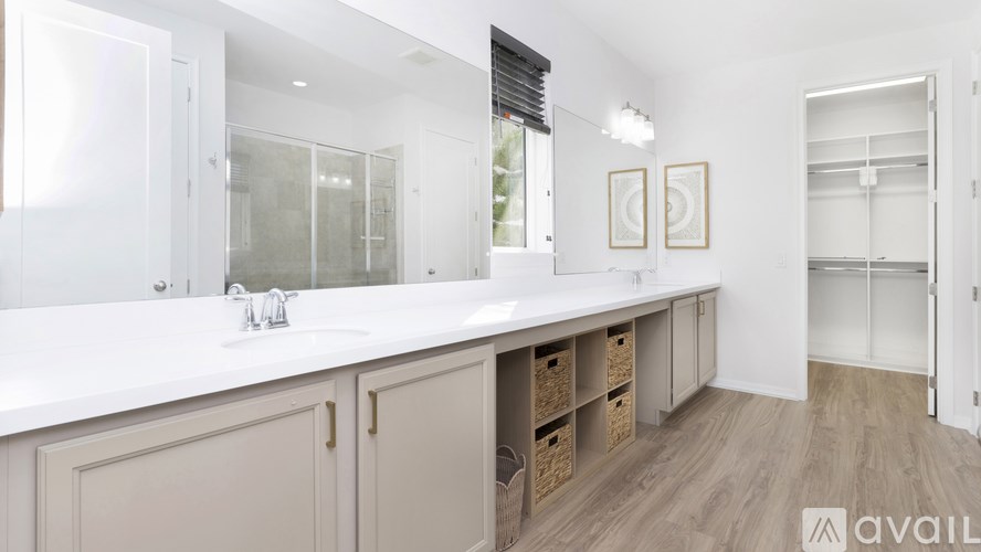 A bathroom with a large mirror, a sink, and a wooden floor.