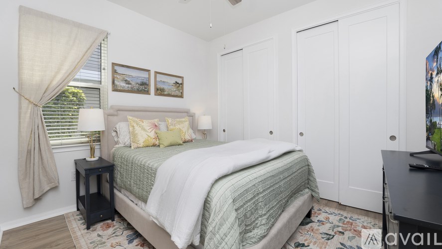 A bedroom with a bed, a nightstand, and a window with curtains.