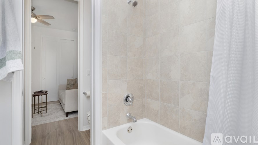 A bathroom with a tub, shower, and a bedroom with a bed and a table.