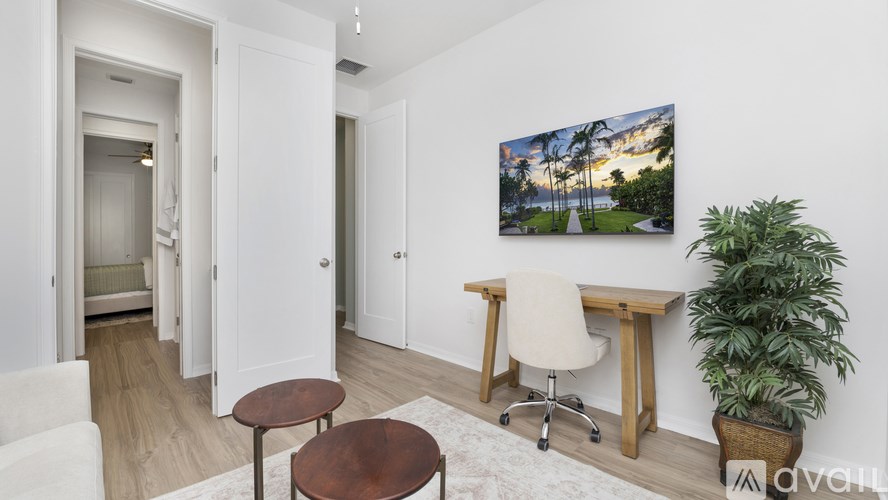 A room with a desk, chair, and potted plant.