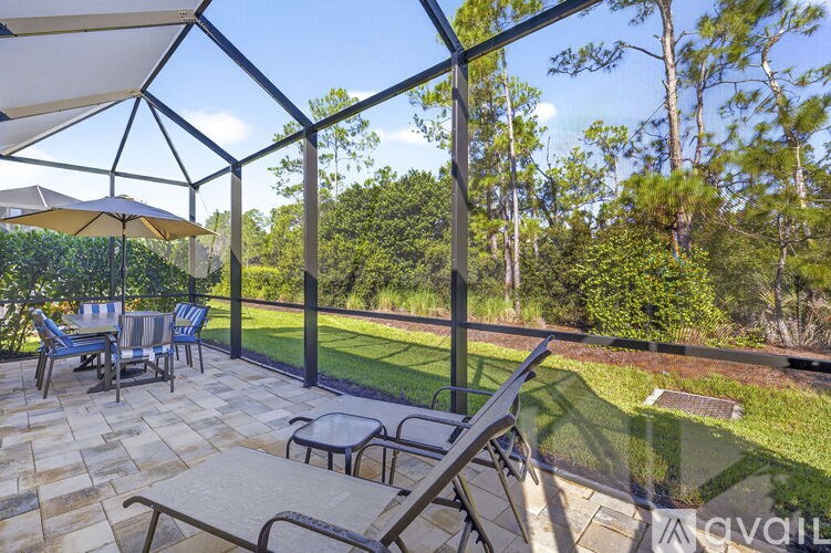 A patio with a table and chairs overlooks a green lawn and trees.