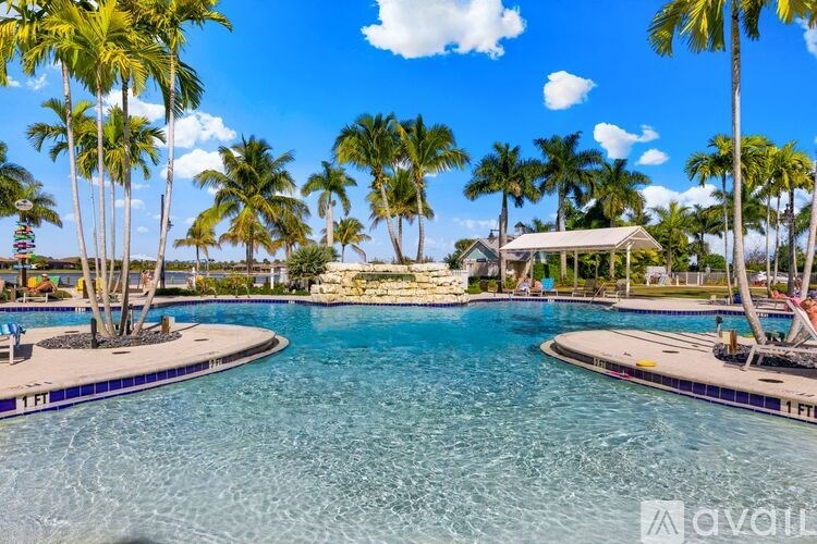 A swimming pool surrounded by palm trees and a clear blue sky.