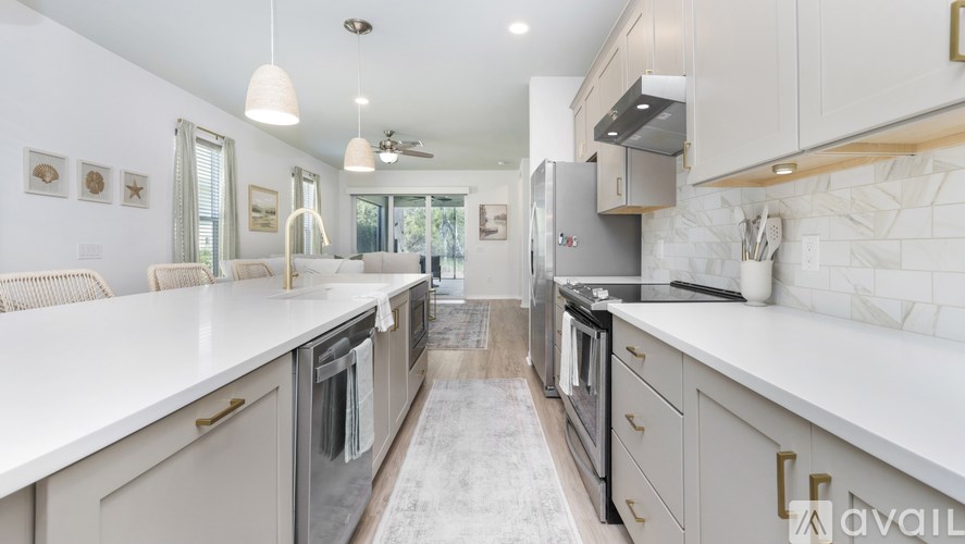 A modern kitchen with white countertops and stainless steel appliances.