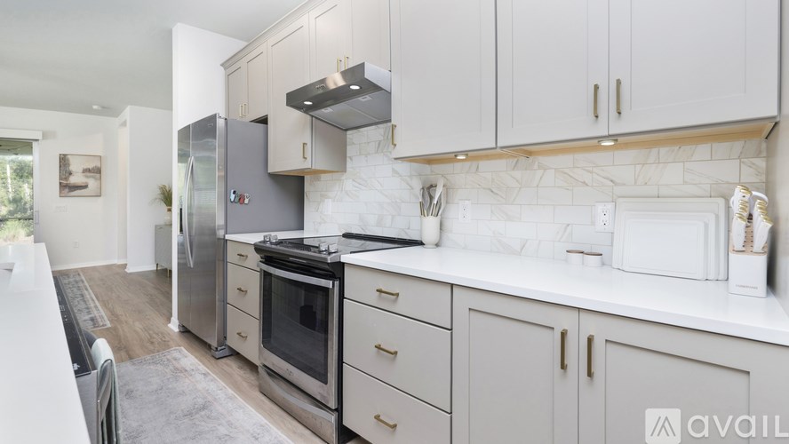 A kitchen with white cabinets and a marble backsplash.