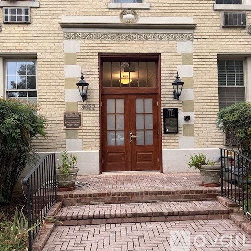 A brown door is flanked by two black lamps.