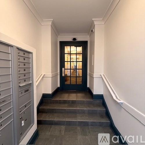 A hallway with a black door and a set of stairs.