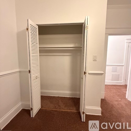 A white closet with a carpeted floor and a white door.