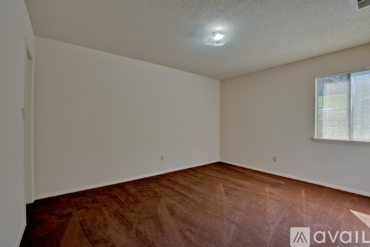 A room with a brown floor and a window with blinds.