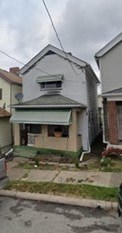 A house with a green awning sits in front of two other houses.