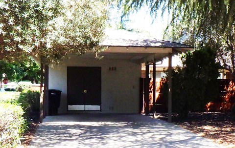 A house with a black trash can in front of it.