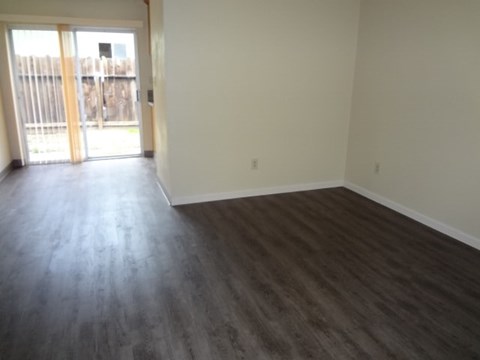 A room with a sliding glass door and wood flooring.