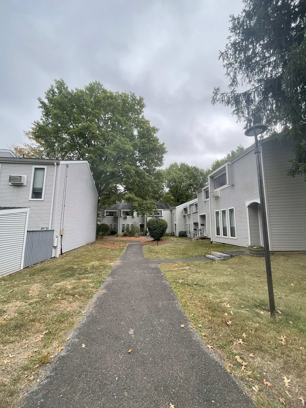 A pathway leads through a grassy area between two buildings.