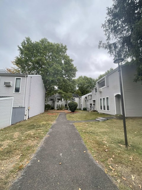 A pathway leads through a grassy area between two buildings.
