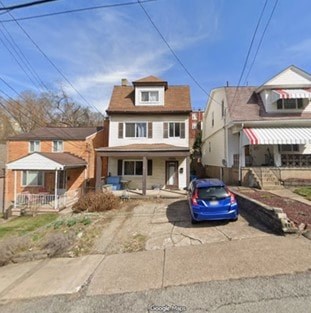 A blue car is parked in front of a house.