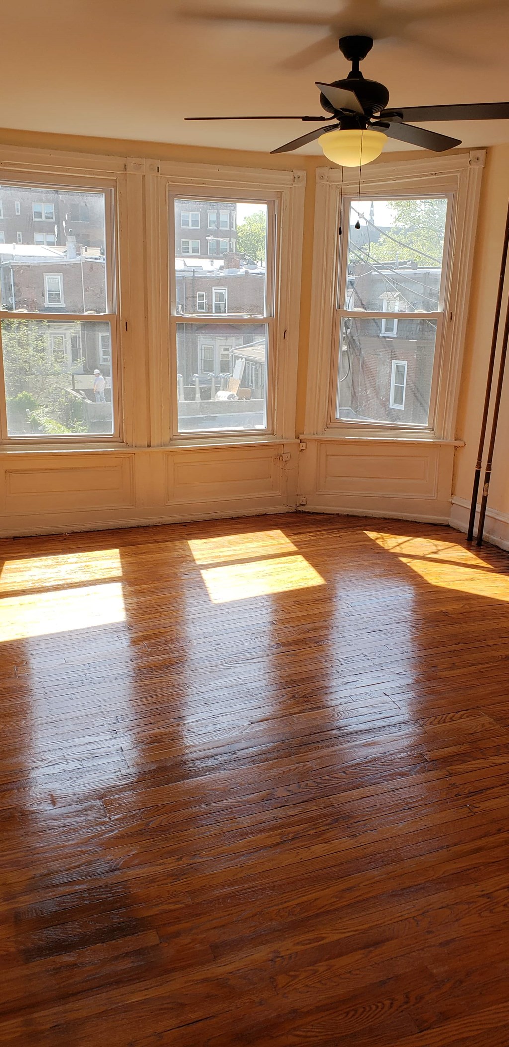 A room with a ceiling fan and a window with a view of a building.