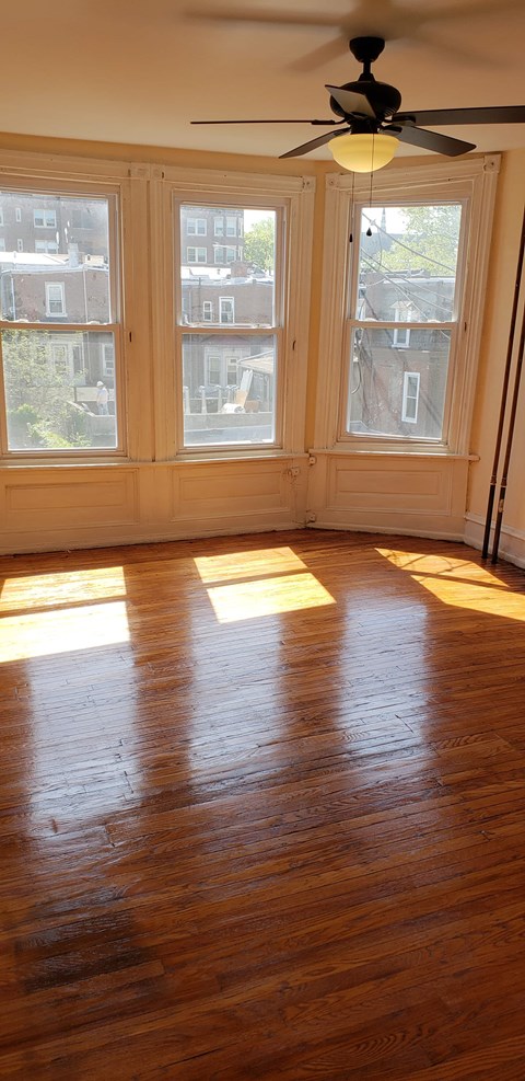 A room with a ceiling fan and a window with a view of a building.