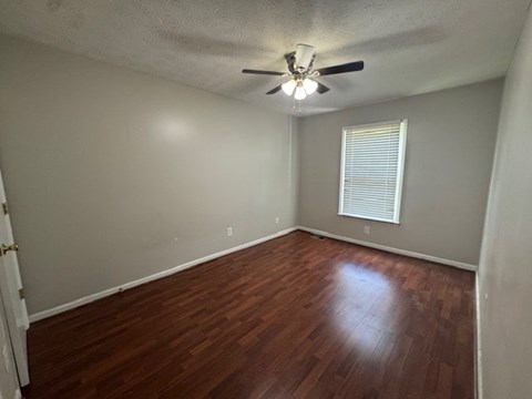 A room with a ceiling fan and wooden flooring.